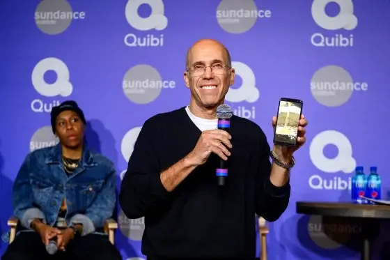 Man houdt een microfoon en toont een smartphone tijdens een Quibi-presentatie op het Sundance-festival.